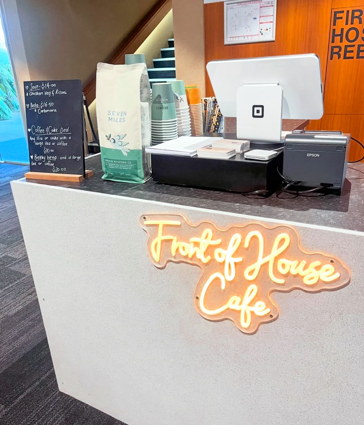 Front of House Cafe counter with neon sign and Seven Miles coffee